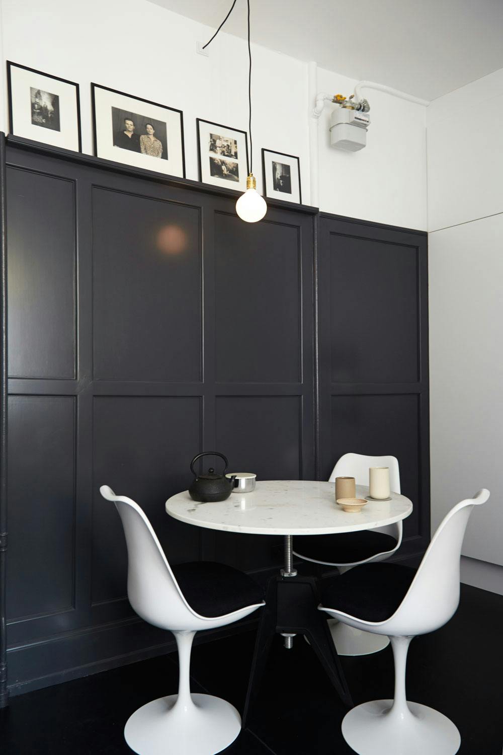 2. Du trenger ikke gå for et helsvart kjøkken Eieren av dette huset har malt en panelvegg bak spiseplassen mørk grå, noe som gir en stilig kontrast til de hvite møblene.